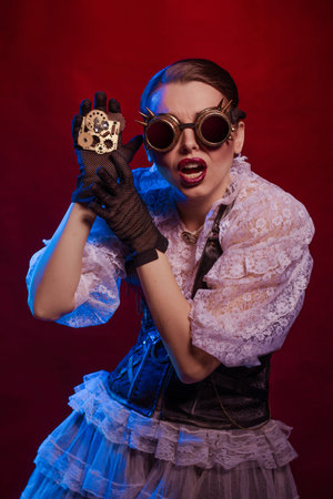 Emotional woman in steampunk costume posing in blue and red stage light