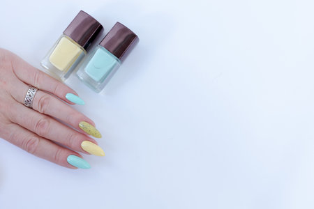 Female hand with long nails and multi-colored bright bottle manicure with nail polish and pen...