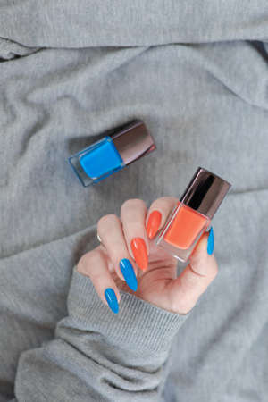 Female hand with long nails and multi-colored bright bottle manicure with nail polish and pen markersの写真素材