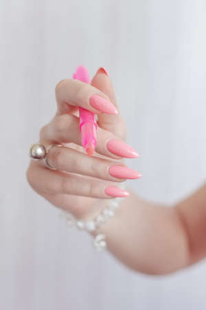Woman's hands with long nails and pink fuchsia bottle manicure with nail polishの写真素材