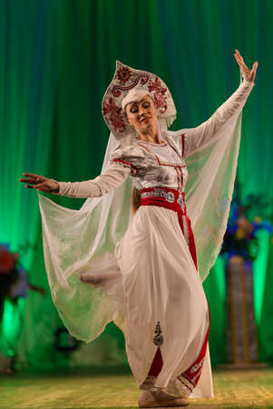 Young woman ballerina in a white suit with a crown on her head performs with a performance on stage in a theaterの写真素材