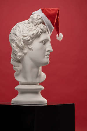 White Plaster Statue of Apollo Belvedere in a red cap of Santa Clausの写真素材