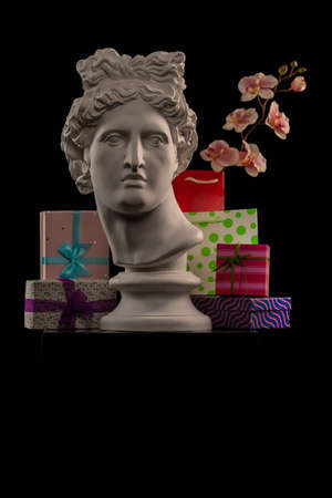 Statue of Apollo Belvedere, flowers and gifts boxes and packages, spotlights and multi-colored backgrounds.の写真素材