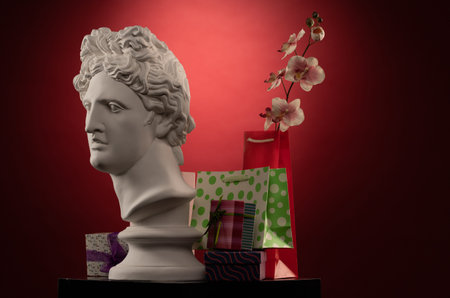 Statue of Apollo Belvedere, flowers and gifts boxes and packages, spotlights and multi-colored...