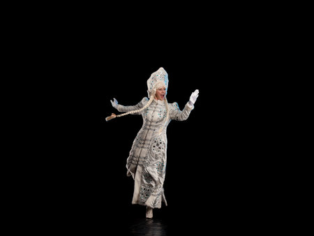 Snow Maiden in a white fur coat and kokoshnik poses on a black background