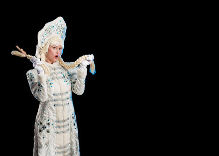 Snow Maiden in a white fur coat, kokoshnik and long hair braids posing on a black backgroundの写真素材