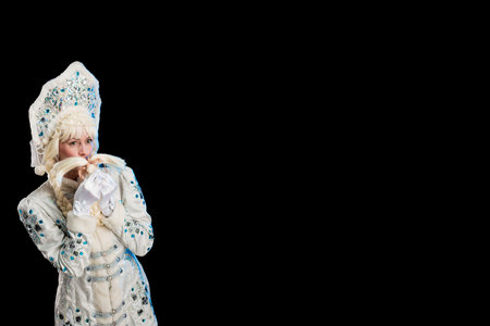 Snow Maiden in a white fur coat and kokoshnik poses on a black background
