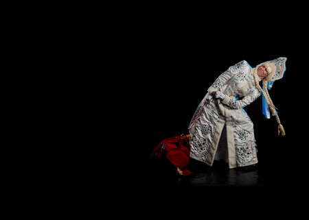 Snow Maiden in a white fur coat and kokoshnik poses on a black backgroundの写真素材