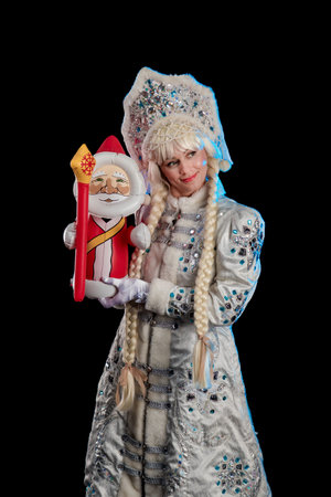 Snow Maiden in a white fur coat, kokoshnik and long hair braids posing on a black background