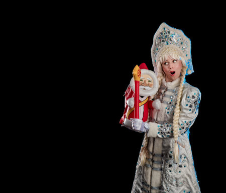 Snow Maiden in a white fur coat, kokoshnik and long hair braids posing on a black background