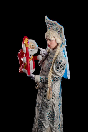 Snow Maiden in a white fur coat, kokoshnik and long hair braids posing on a black backgroundの写真素材