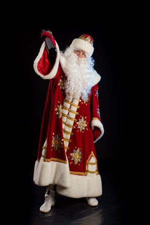 Santa Claus in a red fur coat, with a white beard with a baseball bat in his hands, posing on a...