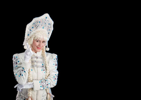 Snow Maiden in a white fur coat and kokoshnik poses on a black backgroundの写真素材