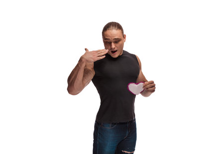 Portrait of a brutal man bodybuilder athlete with a soft toy heart in hands on a white background