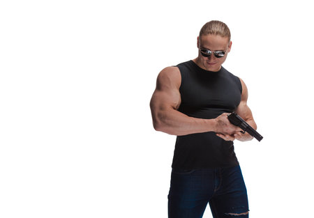 Portrait of a brutal man bodybuilder in sunglasses with a gun on a white backgroundの写真素材