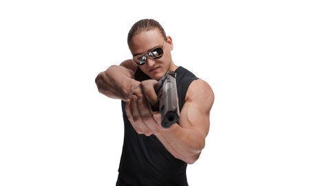 Portrait of a brutal man bodybuilder in sunglasses with a gun on a white background