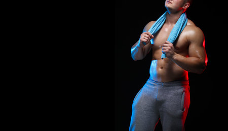 male bodybuilder athlete with torso with a towel posing on a black background, in red and blue light