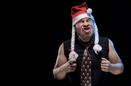 Emotional comic actor man in cap with braids gesticulates on a black background, in anticipation of...