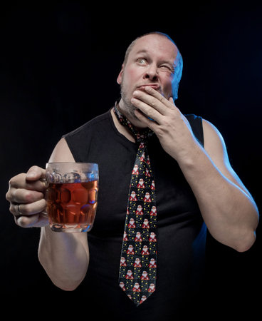 Comic actor man in cap with braids with a glass of beer on a black background, in anticipation of Christmas and New Yearの写真素材