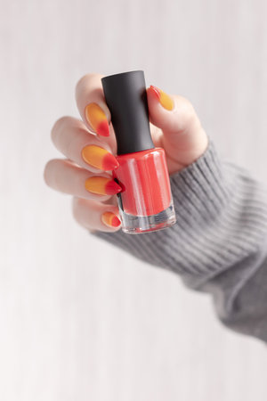 Female hands with long nails with yellow and red nail polish