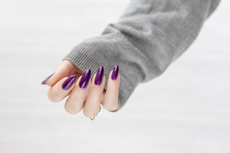 Womans hands with long nails with violet purple nail polishの写真素材