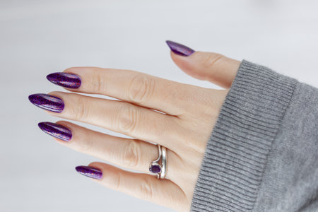 Womans hands with long nails with violet purple nail polishの写真素材