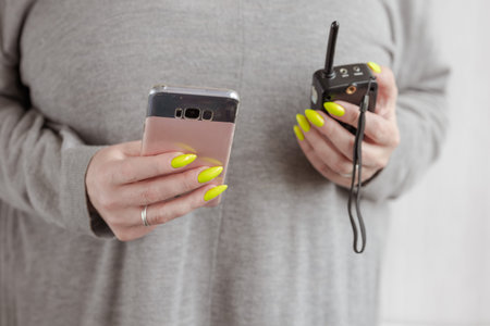 Female hand with long nails and a bottle of bright neon yellow nail polish