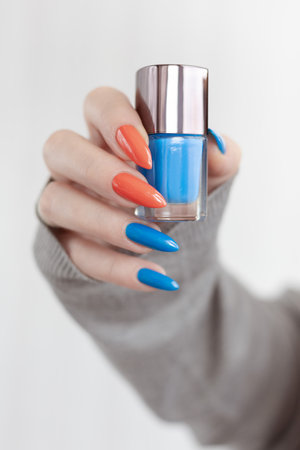 Female hand with long nails and multi-colored bright neon bottle manicure with nail polish and pen markersの写真素材
