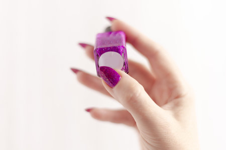 Female hand with long nails and pink fuchsia bottle manicure with nail polishの写真素材