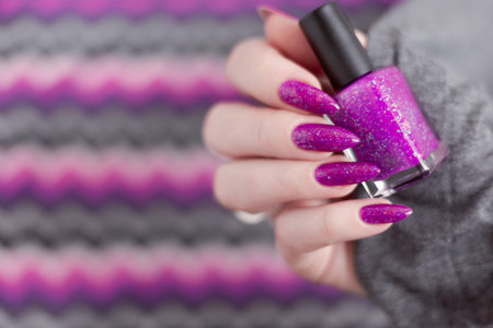 Female hand with long nails and pink fuchsia bottle manicure with nail polishの写真素材