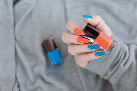 Female hand with long nails and multi-colored manicure, bottles of nail polishesの写真素材