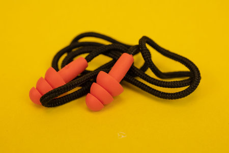 Silicone ear plugs for human ears on yellow background