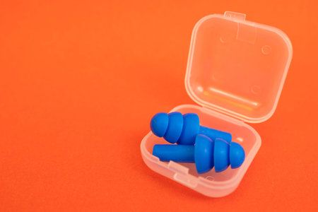 Silicone ear plugs for human ears on red background