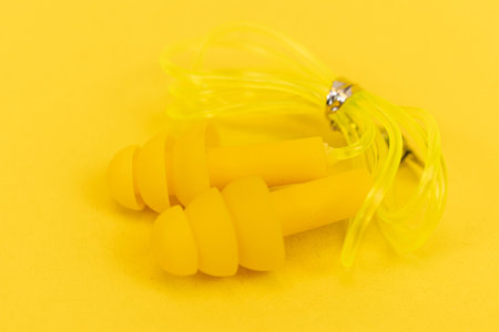 Silicone ear plugs for human ears on yellow background