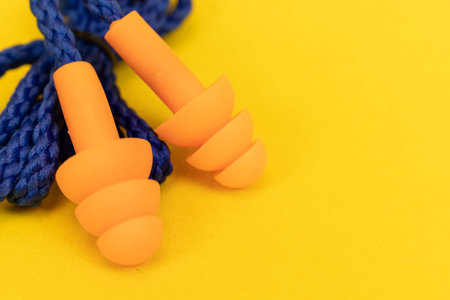 Silicone ear plugs for human ears on yellow background