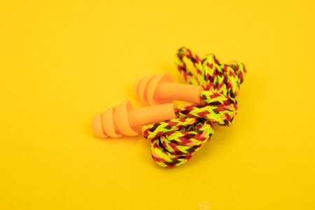 Silicone ear plugs for human ears on yellow background
