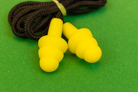 Silicone reusable ear plugs for human ears on green background