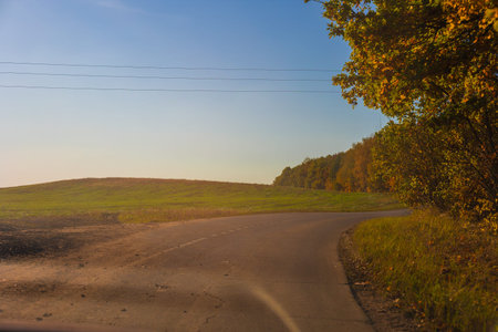 Autumn landscape and view of the road with cars. Orange evening sun and reflections on cars.