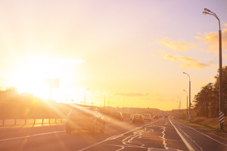 Autumn landscape and view of the road with cars. Orange evening sun and reflections on cars.の写真素材