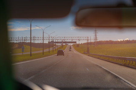 Autumn landscape and view of the road with cars. Orange evening sun and reflections on cars.