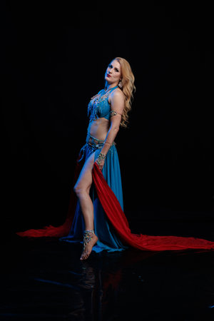 Woman in a blue costume dancer posing and dancing on a black backgroundの写真素材