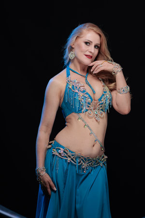 Woman in a blue costume oriental dancer posing and dancing on a black backgroundの写真素材