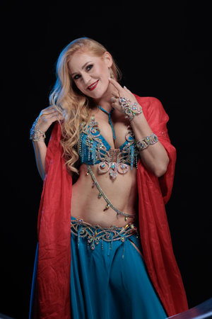 Woman in a blue costume oriental dancer posing and dancing on a black backgroundの写真素材