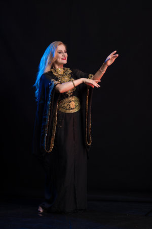 girl with long hair in oriental dancer costume posing and dancing on a black backgroundの写真素材