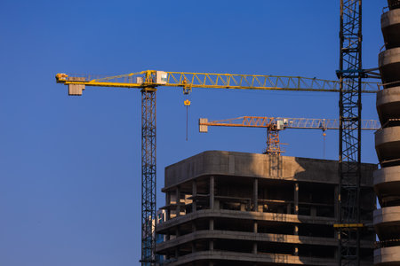 Construction of buildings and high-rise cranes against the evening skyの写真素材