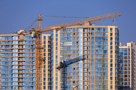 Construction of buildings and high-rise cranes against the evening sky