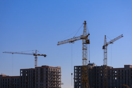 Construction of buildings and high-rise cranes against the evening skyの写真素材