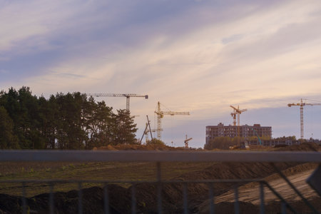 Construction of buildings and high-rise cranes against the evening sky