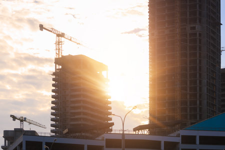 Construction of buildings and high-rise cranes against the evening skyの写真素材