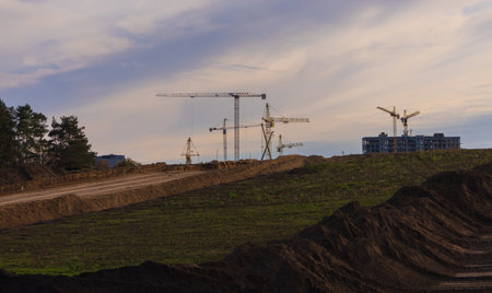 Construction of buildings and high-rise cranes against the evening skyの写真素材